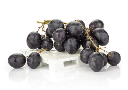Black purple grape cluster (autumn royal variety) on a wooden pallet isolated on white background.