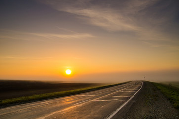 The disk of the sun rising in the early morning fog in rural areas