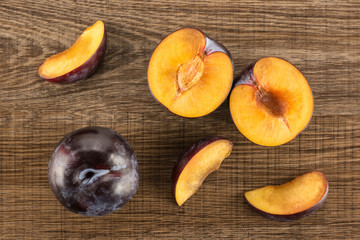 Red blue plums set table top isolated on brown wood background one whole two section halves three slices.