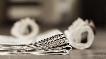 Newspapers folded and rolled, stacked in a pile daily papers with news. Side view, close up