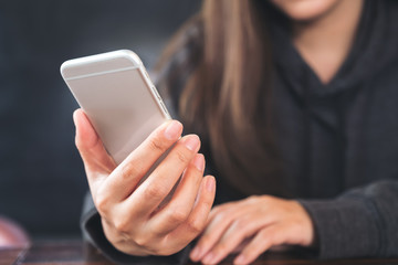 Closeup image of a woman holding , using and looking at smart phone