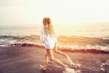 Fototapeta premium Romantic couple having fun on the beach. Happy couple running on beach at sunset.