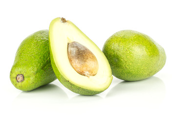Two green smooth avocado and one sliced half with a brown seed isolated on white background bacon variety.