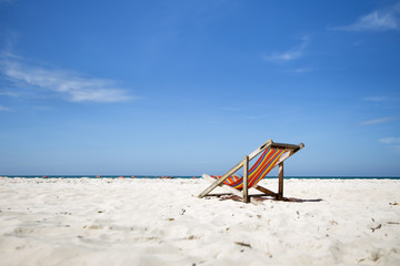 Beautiful beach. Chairs on the sandy beach near the sea. Summer holiday and vacation concept. Tropical beach. Beach chairs on the white sand with cloudy blue sky.