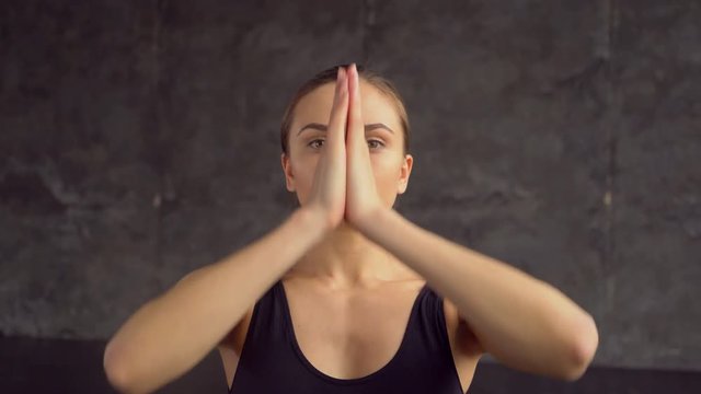 Young woman sitting in lotus yoga pose practicing meditation. Young adult female doing yoga at home. 4 k Young woman sitting in lotus yoga pose practicing meditation. Namaste hands.