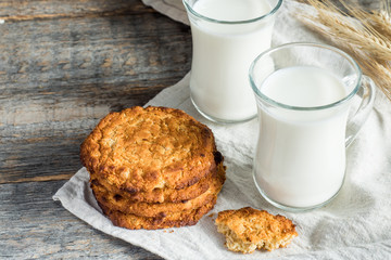 Fresh healthy milk and oatmeal cookies with cereals on wooden rustic background