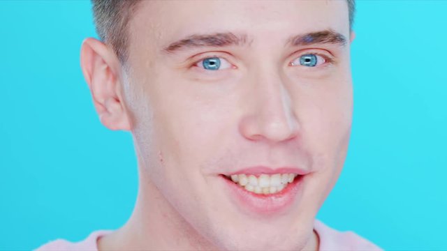 Close-up of a young man with positive emotions.The guy turns his head to the side and smiles happily.