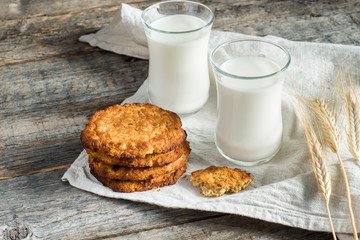 Fresh healthy milk and oatmeal cookies with cereals on wooden rustic background