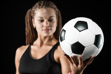 Young female soccer player standing and holding the ball