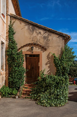 Fototapeta na wymiar View of traditional colorful house in ocher and bindweed under a sunny blue sky, in the city center of Roussillon village. Located in the Vaucluse department, Provence region, southeastern France