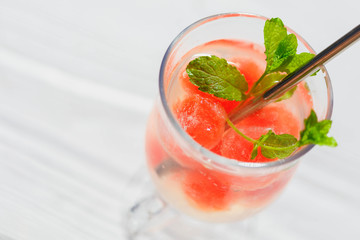 Frozen watermelon balls in a glass of mineral water with beautiful shadows, refreshing drink, clean eating,balance and healthy food and diet  concept
