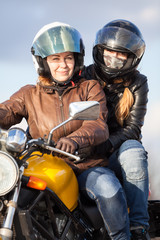 Fototapeta na wymiar Two European women driving together on one bike, passenger sitting behind driver