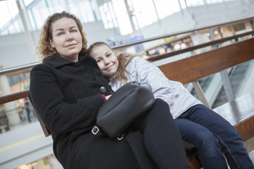 Caucasian mother and young daughter waiting flight departure in airport lounge