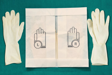 Disposible sterile rubber,one time used Gloves with paper package on green signature of surgery dress