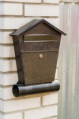 A metal mailbox attached to brick fence posts
