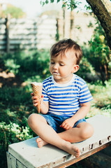 cute little boy in the Park or garden eating ice cream in summer t-shirt