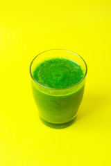 Glass with Green Fresh Smoothie from Leafy Greens Vegetables Fruits Bananas Kiwi Cucumber Apple Spinach on Yellow Background. Healthy Lifestyle Detox Vitamins Alkaline Food. Copy Space Top View