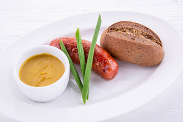 The mutton sausage fried on olive oil with feathers of green onions, mustard sauce and roll of black bread