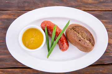 Fried sausage from mutton, is served on white a plate and a dark wooden background
