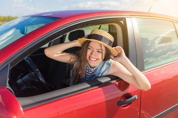 Young woman in car. Girl driving a car.  Smiling young woman sitting in red car
