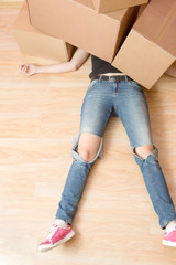 Image of woman in jeans lying under cardboard boxes