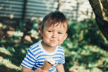 a child in a t-shirt on a bench eating ice cream in the summer is very greedy