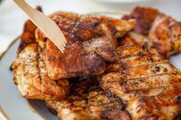 Grilled steak at the campsite lies in a white plate on the table with fork