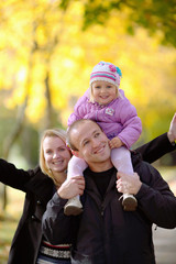 The happy young family walks on the autumn park
