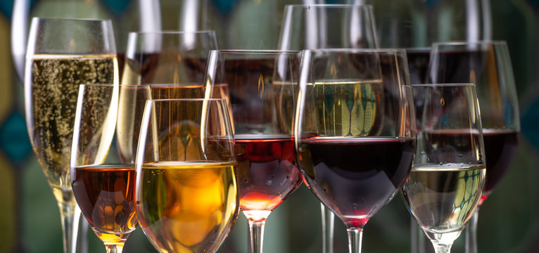 Champagne, white, rose and red wins and drinks in glasses on stained glass background