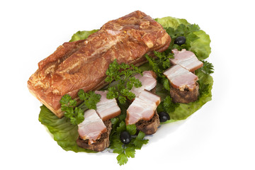 A piece of smoked meat on a clay plate with fresh seasonings with sliced slices.