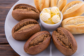 Butter with black and white loaf on a white plate and a dark background