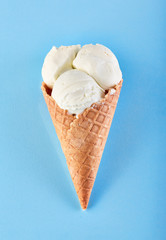 ice cream balls in a Waffle Cone on a Blue Background. Vanilla ice cream in a waffle cone.