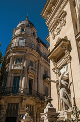 Close-up of buildings in the city center of Nimes, with statues, decorative details on the walls...