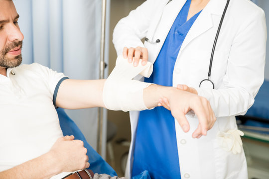 Doctor putting bandage on wounded arm