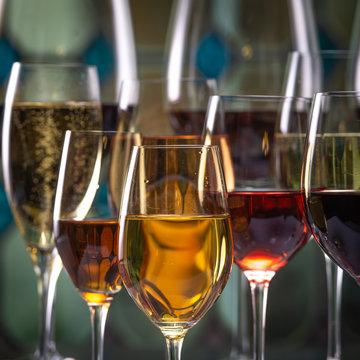Champagne, white, rose and red wins and drinks in glasses on stained glass background