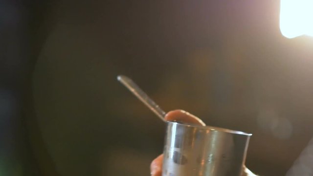 Closeup of bartender pouring drink into the glass with beautifully preapred decoration.Barman mixing exotic drink