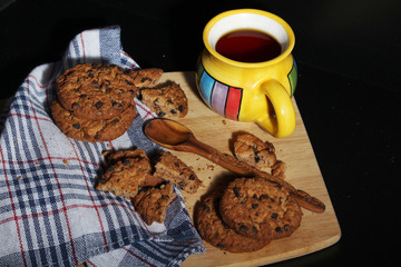 Cookies with chocolate chips and tea against dark background