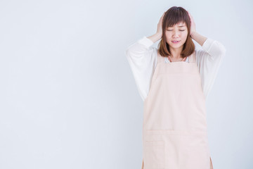 耳をおさえるエプロン姿の女性
