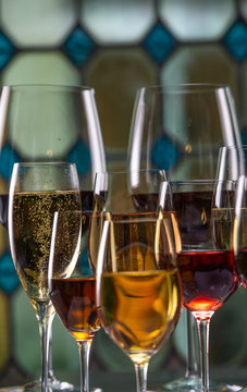 Champagne, white, rose and red wins and drinks in glasses on stained glass background