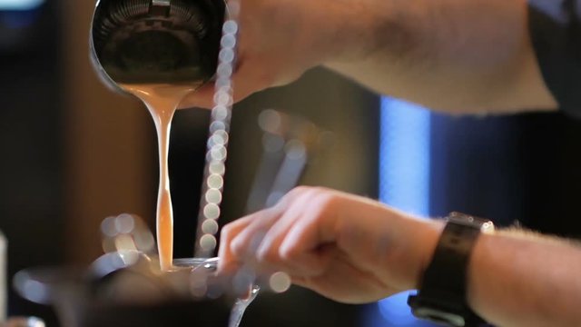 Closeup of bartender pouring drink into the glass with beautifully preapred decoration.Barman mixing exotic drink