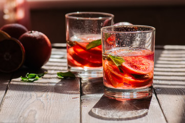 Refreshing blood orange water or infused water in a glass on a wooden background.