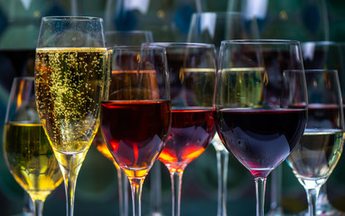 Champagne, white, rose and red wins and drinks in glasses on stained glass background