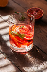 Refreshing blood orange water or infused water in a glass on a wooden background.