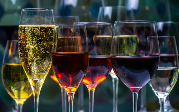 Champagne, white, rose and red wins and drinks in glasses on stained glass background