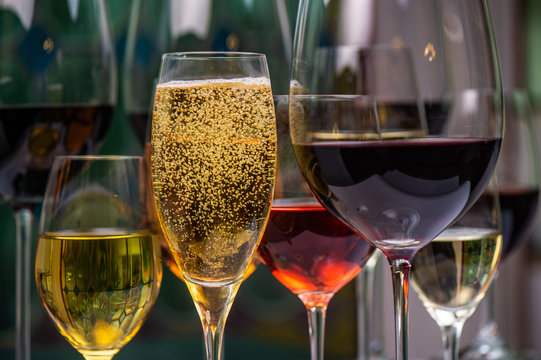 Champagne, white, rose and red wins and drinks in glasses on stained glass background