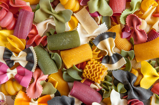 Mixed selection of dried pasta on wooden background. Macaroni scattered on a glass jar. Background. Close up
