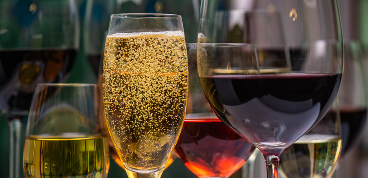 Champagne, white, rose and red wins and drinks in glasses on stained glass background