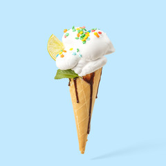 Ice cream in a horn with lime, mint and chocolate topping on a blue background.