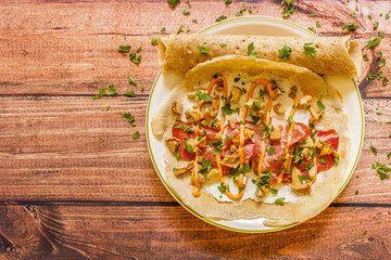 Crepes on plate with cream cheese, mushrooms, sauce, smoked ham and parsley- homemade healthy  food, wooden background
