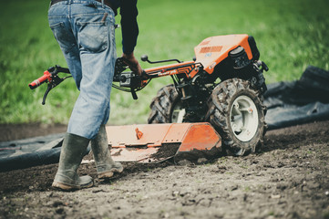 farmer with motor cultivator prepares the ground in spring